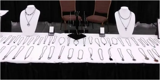 Kim's Unique Boutique jewelry display table at a craft show — necklaces and bracelets on dark tablecloth